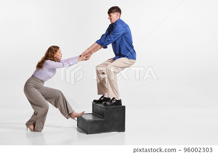 Portrait of man and woman, employees helping each other in professional sphere isolated over white background Portrait of man and woman, employees helping each other in professional sphere isolated over white background 96002303