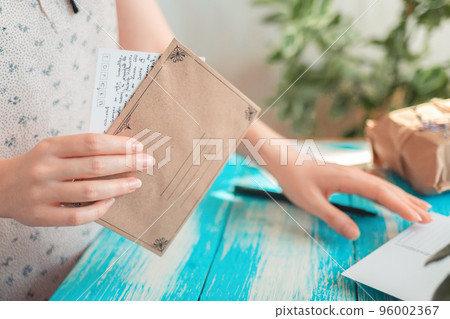 A woman holds an empty envelope with a letter in her hand. Hands close-up. The concept of a mail message and postcrossing 96002367