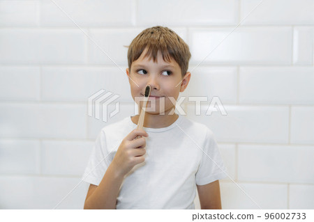 cute 8 years old boy brushing teeth with bamboo tooth brush with black bristles in bathroom. cute 8 years old boy brushing teeth with bamboo tooth brush with black bristles in bathroom. 96002733
