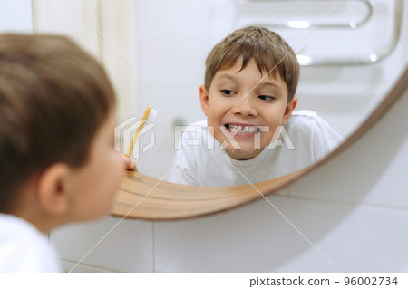 cute 8 years old boy washing face in bathroom looking in mirror and smiling. cute 8 years old boy washing face in bathroom looking in mirror and smiling. 96002734