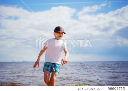 Happy little boy is running in the sea on sunny summer day. Childhood concept Happy little boy is running in the sea on sunny summer day. Childhood concept 96002735