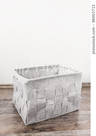 Empty home storage basket made of soft grey felt material. Side view, square pattern, copy space 96003715