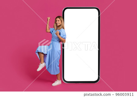 Glad excited mature european lady make success gesture with hand, celebrate victory near big phone with blank screen 96003911
