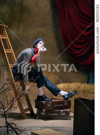 Vintage portrait of male mime artist expressing sadness and loneliness over dark retro circus backstage background. Concept of emotions, art, fashion, style Vintage portrait of male mime artist expressing sadness and loneliness over dark retro circus backstage background. Concept of emotions, art, fashion, style 96004192