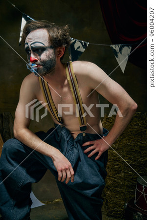 Sad male clown is sad, going through a personal tragedy, despair in the old retro circus backstage. Concept of fate, job, emotions, facial expression, mental health 96004207