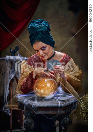 Portrait of magnificent fortune teller woman reading future on magical crystal ball and tarot cards. Concept of vintage style, retro circus, art, fate 96004250