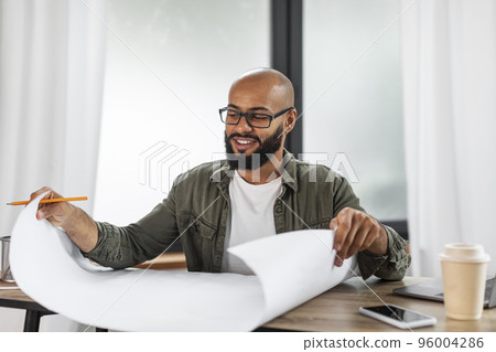 Happy mature latin industrial engineer looking at project drawings work at table, working at office interior, copy space Happy mature latin industrial engineer looking at project drawings work at table, working at office interior, copy space 96004286