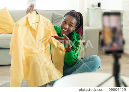 Happy black female blogger making video review with new clothes after successful shopping, recording video on cellphone 96004439