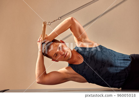 Pilates reformer workout exercises man at gym indoor. 96005018