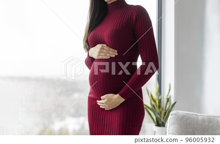 Pregnant woman profile holding her belly in red dress. Beautiful model for pregnancy maternity clothes 96005932