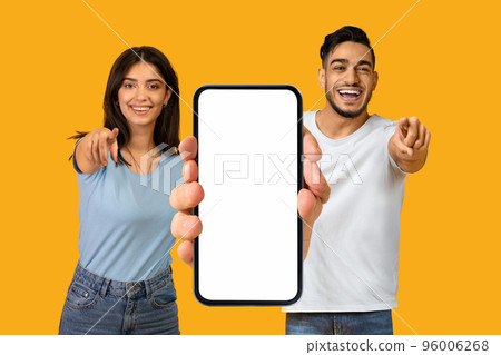 Cheerful Arab Man And Woman Showing Blank Smartphone And Pointing At Camera 96006268