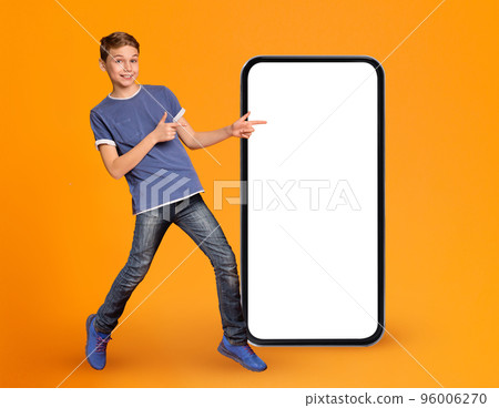 Great App. Joyful Male Kid Pointing At Smartphone With Blank White Screen Great App. Joyful Male Kid Pointing At Smartphone With Blank White Screen 96006270