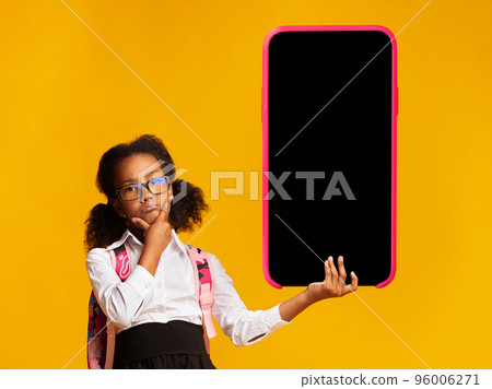 Educational Offer. Pensive Black Schoolgirl Holding Big Smartphone With Blank Screen 96006271