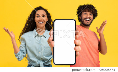 Amazing Offer. Surprised Arab Couple Showing Big Blank Smartphone With White Screen Amazing Offer. Surprised Arab Couple Showing Big Blank Smartphone With White Screen 96006273