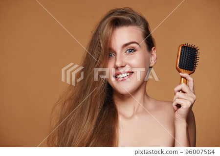 Beautiful smiling brunette woman showing wooden brush Beautiful smiling brunette woman showing wooden brush 96007584