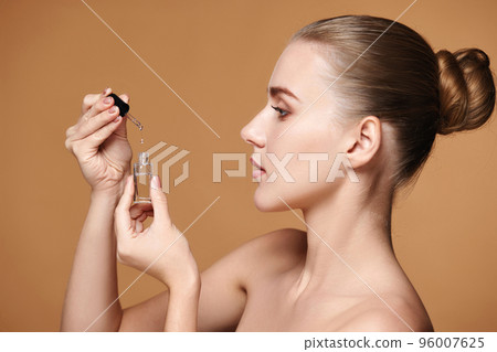 woman holding bottle with serum for skin care 96007625