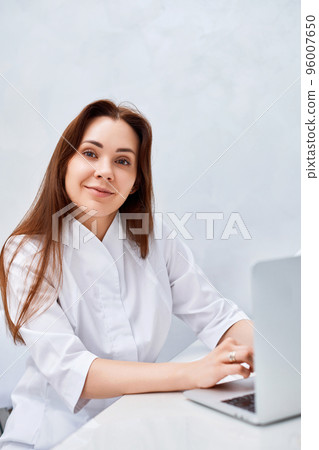 female doctor in white medical uniform using laptop 96007650
