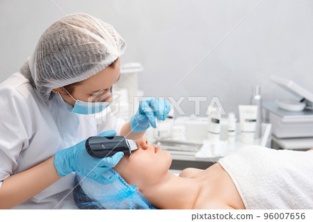 face of woman while procedure ultrasonic cleansing 96007656