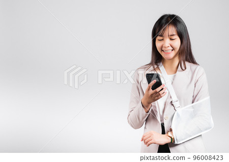 Woman confident smiling broken arm after accident and wear arm splint for treatment and hold smartphone, happy Asian female sling supported hand isolated on white background, social media, copy space Woman confident smiling broken arm after accident and wear arm splint for treatment and hold smartphone, happy Asian female sling supported hand isolated on white background, social media, copy space 96008423