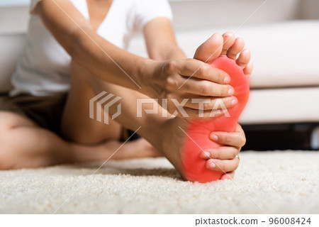 Foot pain, Asian woman feeling pain in her foot at home, female suffering from feet ache use hand massage relax muscle from soles in home interior, Healthcare problems and podiatry medical concept 96008424