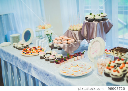 Delicious and tasty dessert table with cupcakes shots at reception closeup 96008720