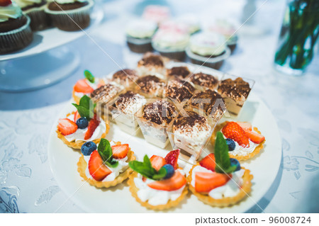 Delicious and tasty dessert table with cupcakes shots at reception closeup 96008724