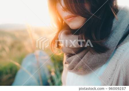 Photo of a woman standing in nature at sunset 96009287