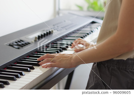 A woman playing an electronic piano 96009605