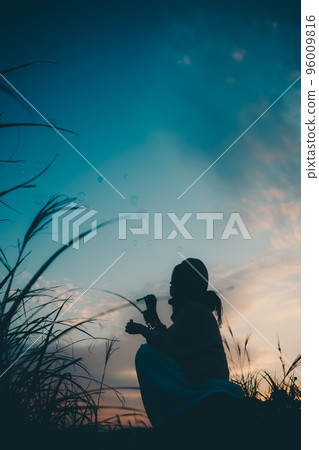 Silhouette photo of a woman standing in nature at sunset Silhouette photo of a woman standing in nature at sunset 96009816