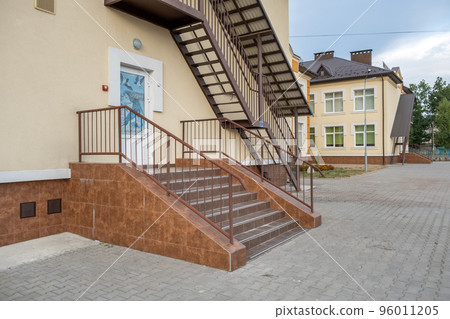 Concrete entrance stairs covered with ceramic tiles with metal railings outdoors. Concrete entrance stairs covered with ceramic tiles with metal railings outdoors. 96011205