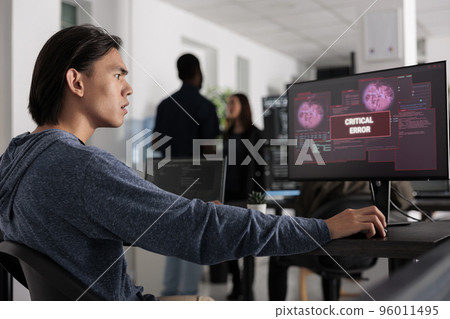 Worried software developer having web server hacked, looking at critical error on computer screen in programming office. Asian web developer trying to solve hacking problem, firewall security. Worried software developer having web server hacked, looking at critical error on computer screen in programming office. Asian web developer trying to solve hacking problem, firewall security. 96011495