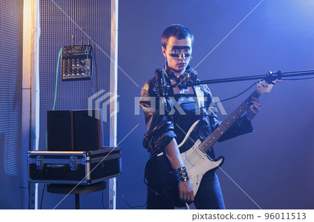 Alternative singer playing guitar and rock song, singing heavy metal music with intrument in studio. Doing live punk rock performance with loud scream, feeling talented and cool at concert show. Alternative singer playing guitar and rock song, singing heavy metal music with intrument in studio. Doing live punk rock performance with loud scream, feeling talented and cool at concert show. 96011513