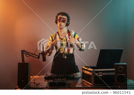 Musical artist doing thumbs up and like sign, showing approval symbol to celebrate success and achievement. Mixing techno music with turntables and expressing positive agreement gesture. 96011541