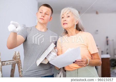 Grandmother and grandson are discussing the drawings of apartment room being renovated Grandmother and grandson are discussing the drawings of apartment room being renovated 96015057