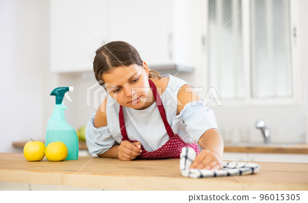 Positive woman cleaning kitchen table at home 96015305
