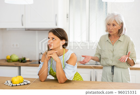 Upset girl at home kitchen while worried elderly mother reprimanding her. Family conflicts concept 96015331