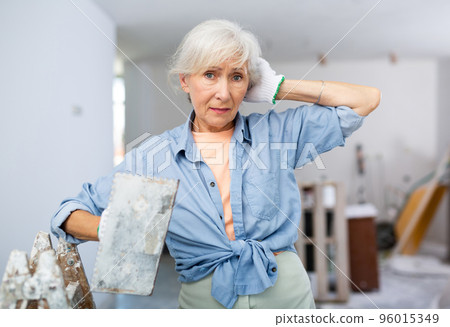 Portrait of positive woman with spatula in her hand in room being renovated Portrait of positive woman with spatula in her hand in room being renovated 96015349