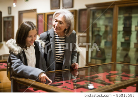 Senior woman and tween girl observing arts and crafts in museum Senior woman and tween girl observing arts and crafts in museum 96015595
