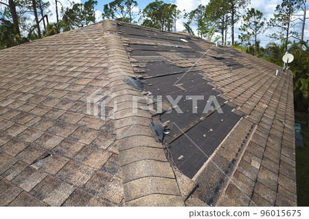 Damaged house roof with missing shingles after hurricane Ian in Florida. Consequences of natural disaster 96015675