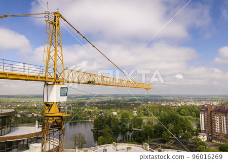 Apartment or office tall building under construction. Brick walls, glass windows, scaffolding and concrete support pillars. Tower crane on bright blue sky copy space background. 96016269