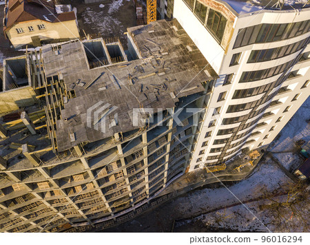 Aerial winter top view of modern developing city with tall apartment complex building under construction, parked cars, roofs and streets. Urban infrastructure, view from above. 96016294