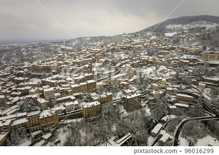 Aerial winter landscape of dense historic center of Thiers town in Puy-de-Dome department, Auvergne-Rhone-Alpes region in France. Rooftops of old buildings and narrow streets at snowfall 96016299