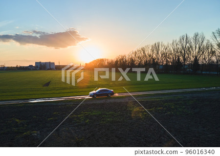 Aerial view of sedan car driving fast on dirt road at sunset. Traveling by vehicle concept. Aerial view of sedan car driving fast on dirt road at sunset. Traveling by vehicle concept. 96016340