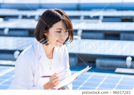 一位身穿白大褂的女士在實驗室測量太陽能電池板 96017281