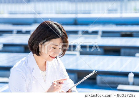 一位身穿白大褂的女士在實驗室測量太陽能電池板 96017282