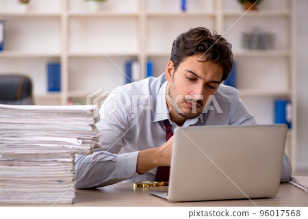Young male employee and too much work in the office 96017568