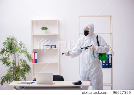 Young male contractor disinfecting office during pandemic 96017599