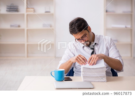 Young male employee unhappy with excessive work in the office 96017873
