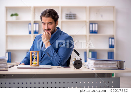 Young male employee in wheel-chair in time management concept Young male employee in wheel-chair in time management concept 96017882
