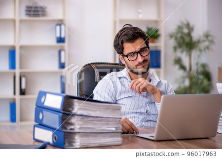 Young male employee unhappy with excessive work in the office 96017963